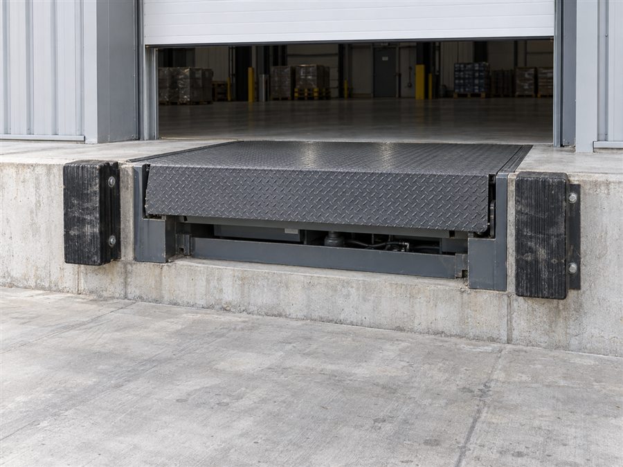 Loading dock leveler and dock bumpers at a warehouse door